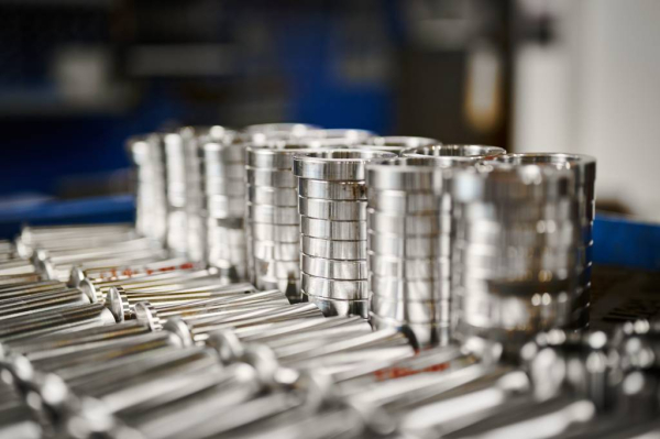 Stacked crank pins and metal rings with a polished finish, showcasing CNC machining precision and surface quality in an industrial setting.